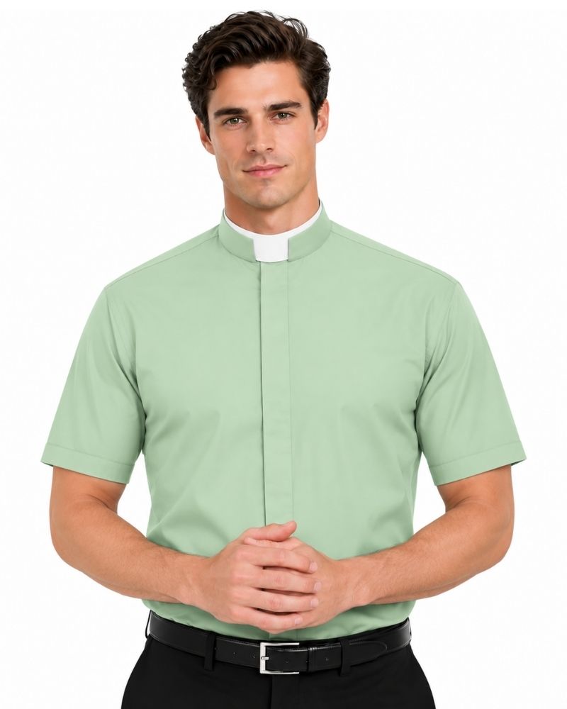 A man wearing a light sage green short-sleeve priest shirt with a white collar, paired with a black belt and black trousers, against a plain white background.