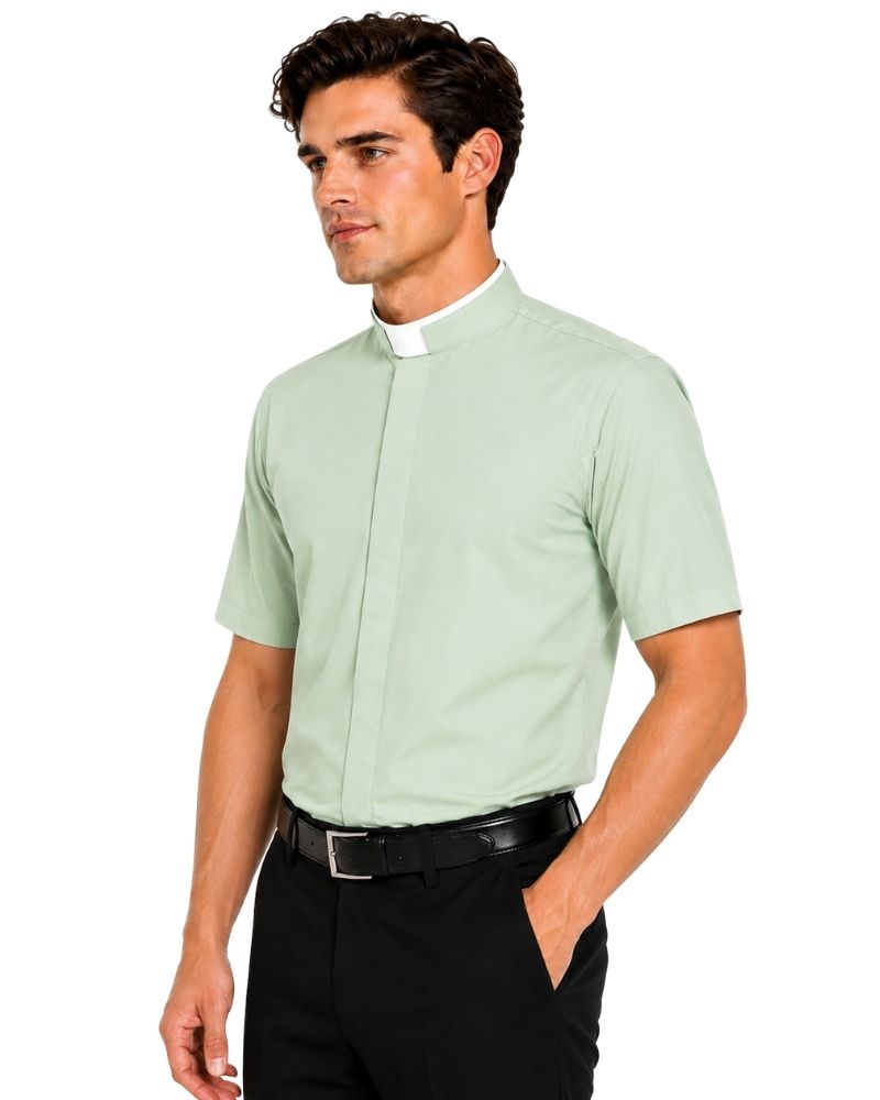 A man wearing a light sage green short-sleeve clerical shirt with a white collar, paired with black trousers and a black belt, shown against a plain white background.