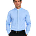 A man wearing a light blue long-sleeve clerical shirt with a white collar tab, paired with black trousers and a black belt, against a plain white background.