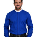 A smiling man wearing a royal blue long-sleeve clerical shirt with a white collar, paired with black trousers and a black belt, against a plain white background.