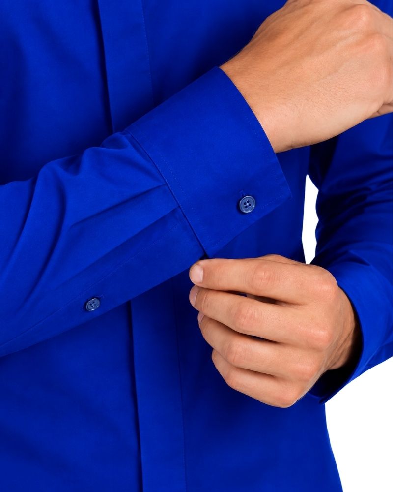 Close-up of a man wearing a bright royal blue long-sleeve clerical shirt and buttoning the cuff.