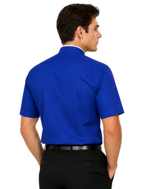 A man shown from the back wearing a royal blue short-sleeve clerical shirt tucked into black dress pants, against a plain white background.
