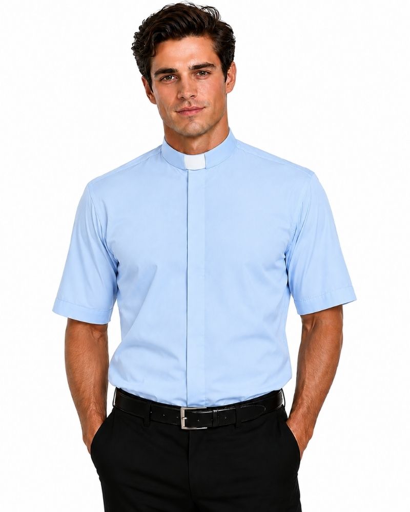 front side view of a man wearing a light blue short sleeve clergy shirt with a white tab collar, paired with black dress pants, shown on a professional studio white background.