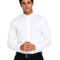 A man wearing a crisp white long-sleeve clerical shirt with a high stand collar, paired with black trousers and a black belt, against a solid white background.