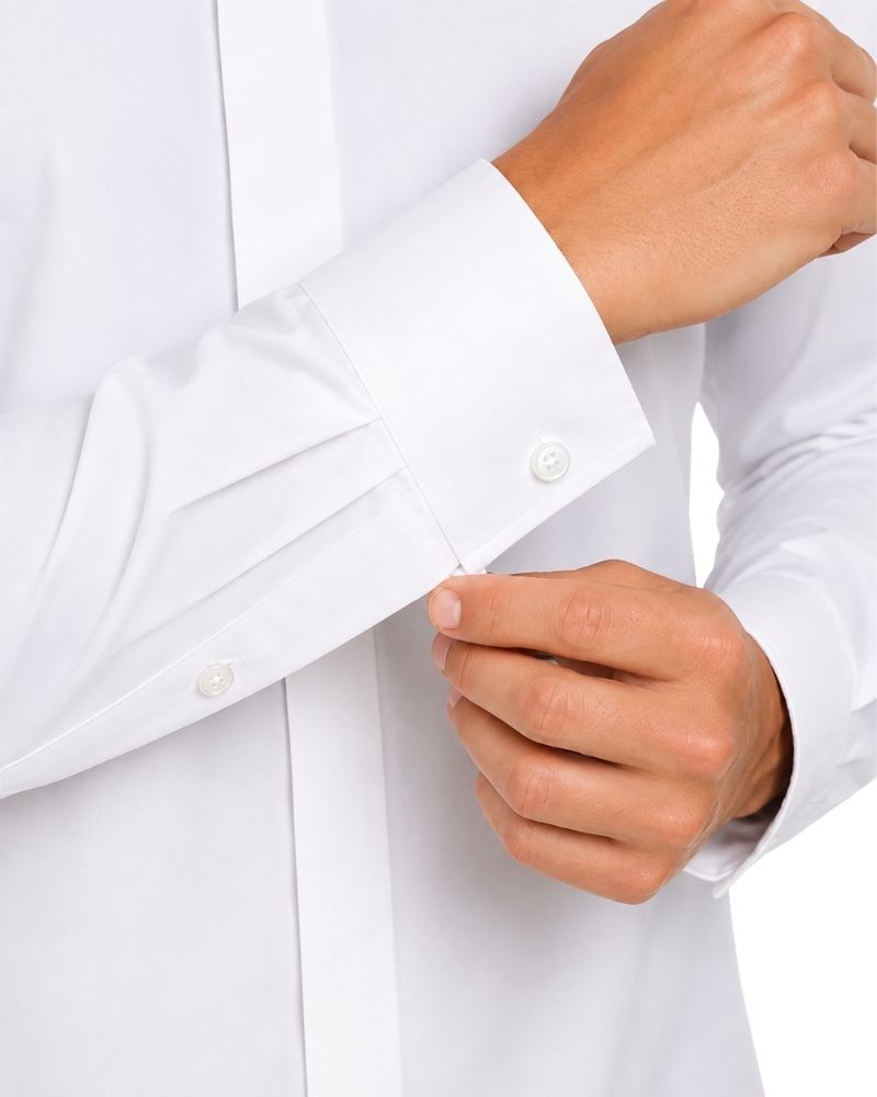 Close-up of a man hands buttoning the cuff of a white long-sleeve dress shirt.