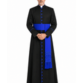 A man wearing a Black Clerical Cassock With Royal Blue Trim with a bright blue sash and matching blue buttons, standing against a plain white background.