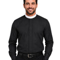 A smiling man wearing a black long-sleeve clerical shirt with a white collar, paired with black trousers and a black belt, against a plain white background.
