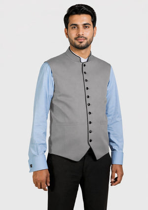 Man wearing a gray vest over a light blue shirt on a white background