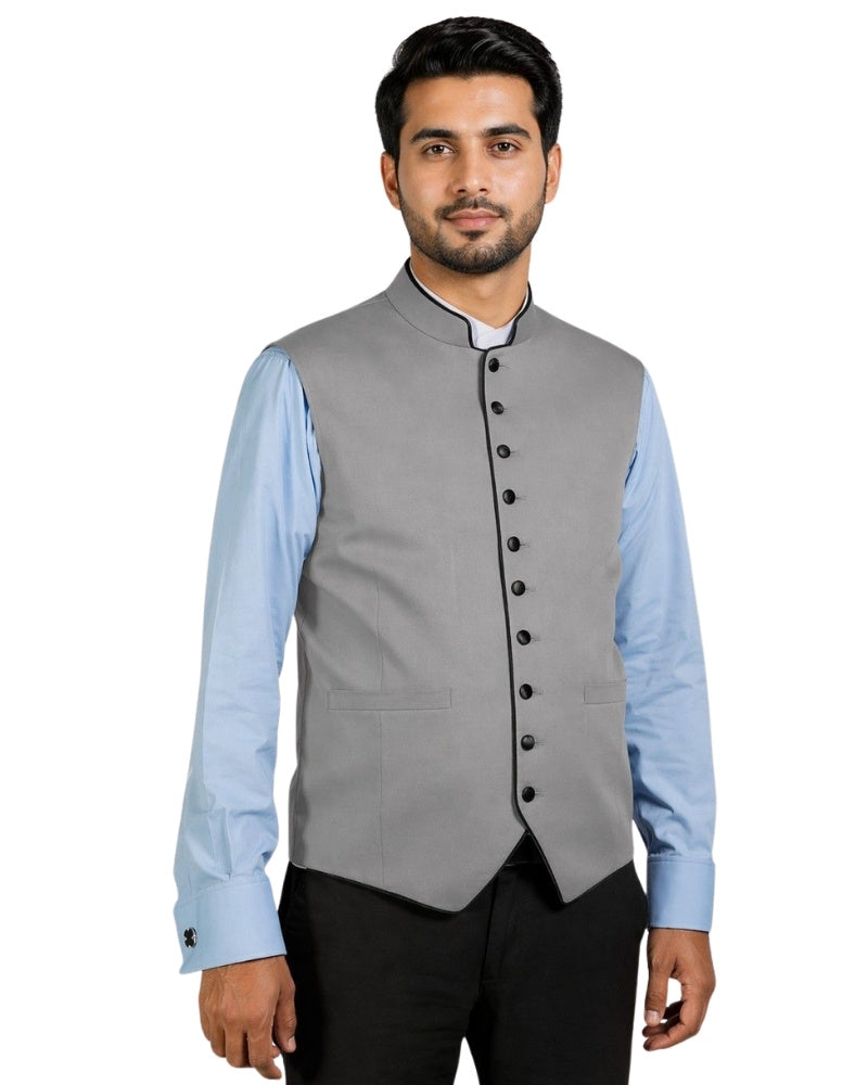 Man wearing a gray vest with black buttons over a light blue shirt on a white background