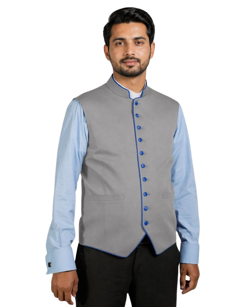Man wearing a gray vest with blue buttons over a light blue shirt on a white background.