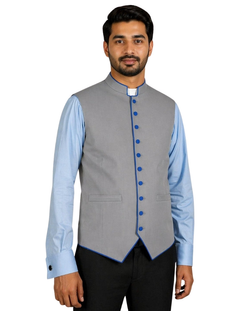 Man wearing a gray vest with blue buttons over a light blue shirt on a white background.