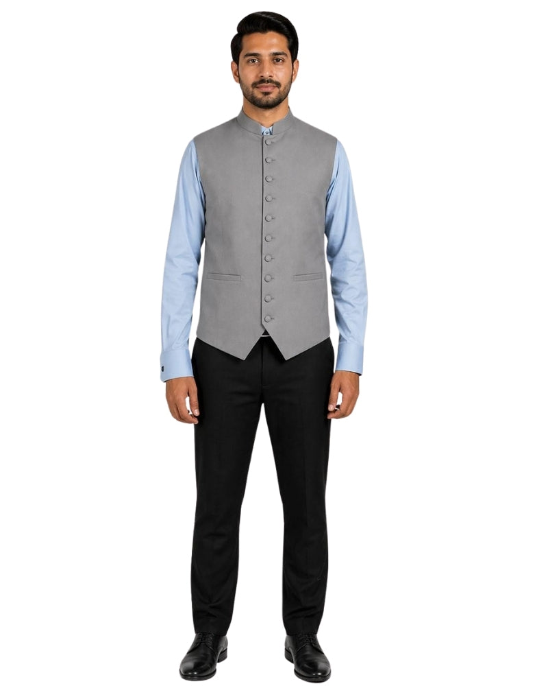Man wearing a gray vest with gray buttons over a light blue shirt on a white background.