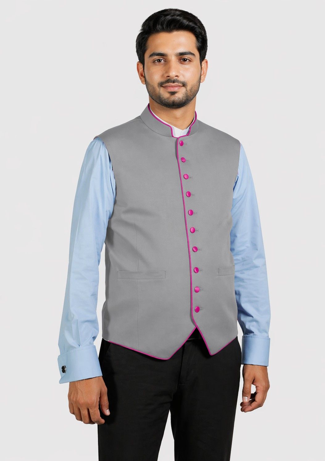 Man wearing a gray vest with pink buttons over a light blue shirt on a white background