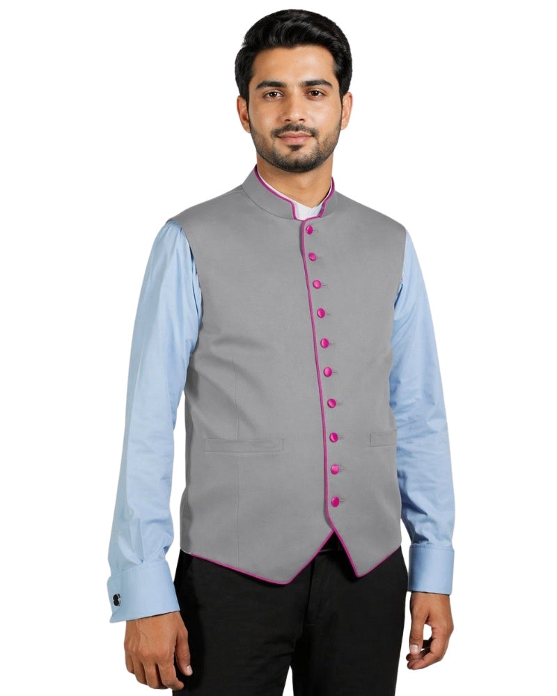Man wearing a gray vest with pink buttons over a light blue shirt on a white background