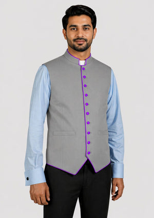 Man wearing a gray vest with purple buttons over a light blue shirt on a white background