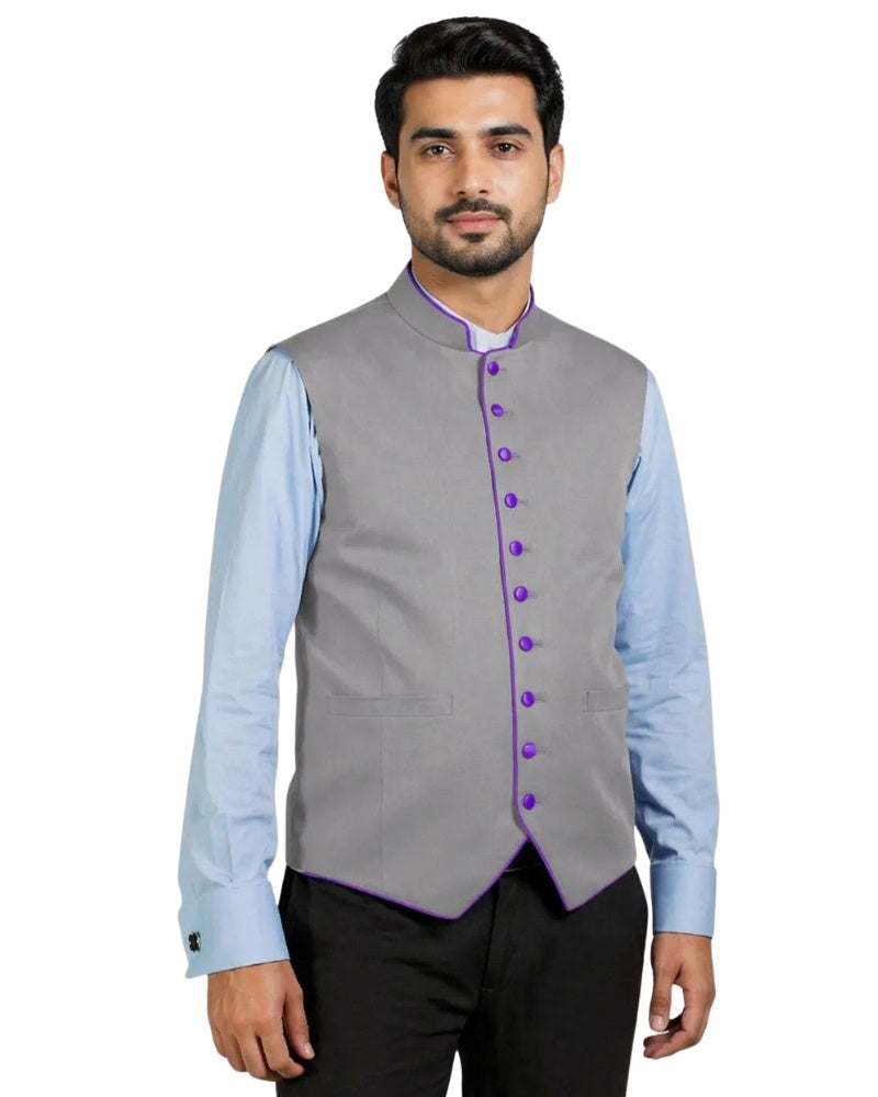 Man wearing a gray vest with purple buttons over a light blue shirt on a white background