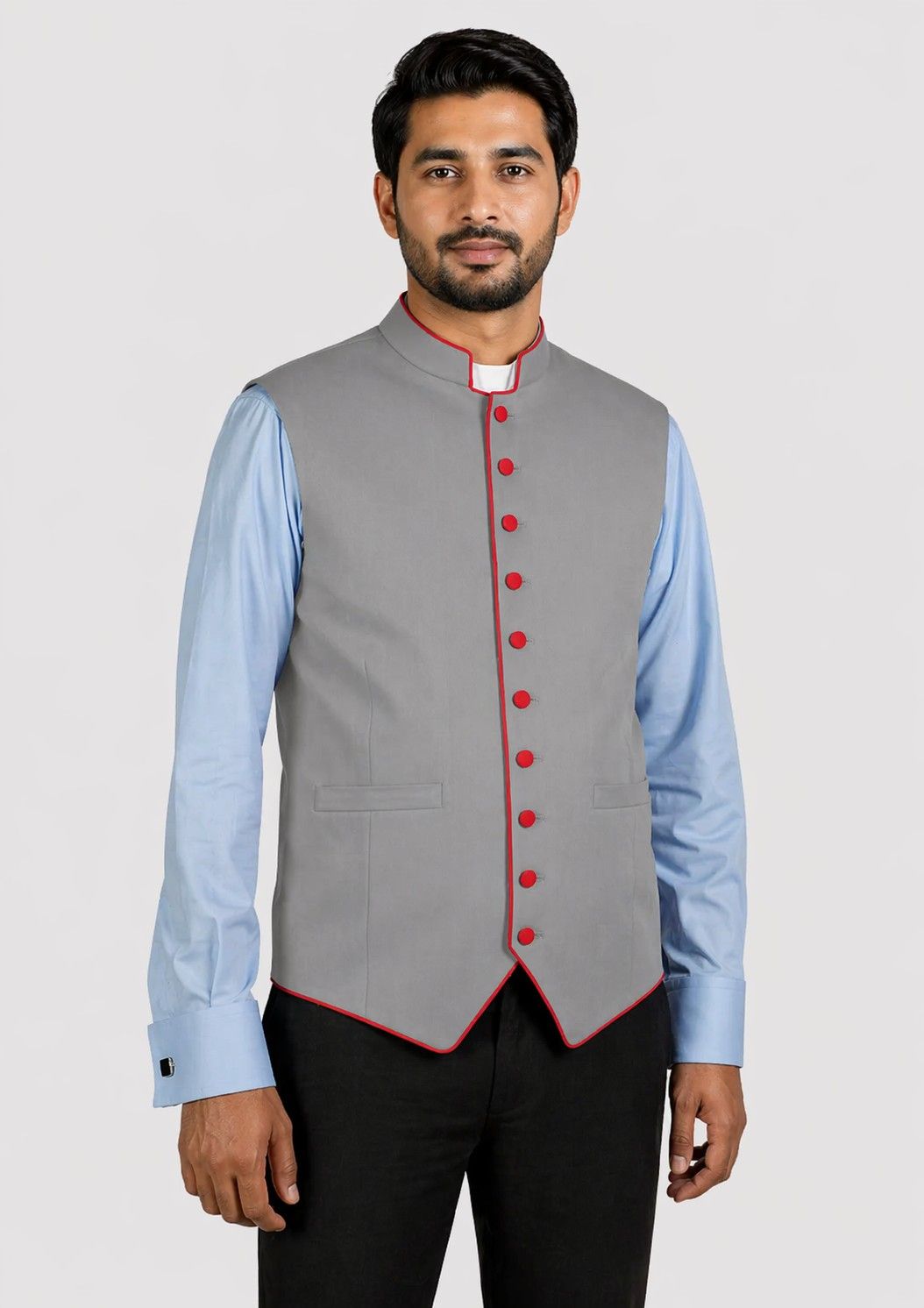 Man wearing a gray vest with red buttons over a light blue shirt on a white background