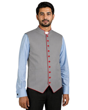 Man wearing a gray vest with red buttons over a light blue shirt on a white background.