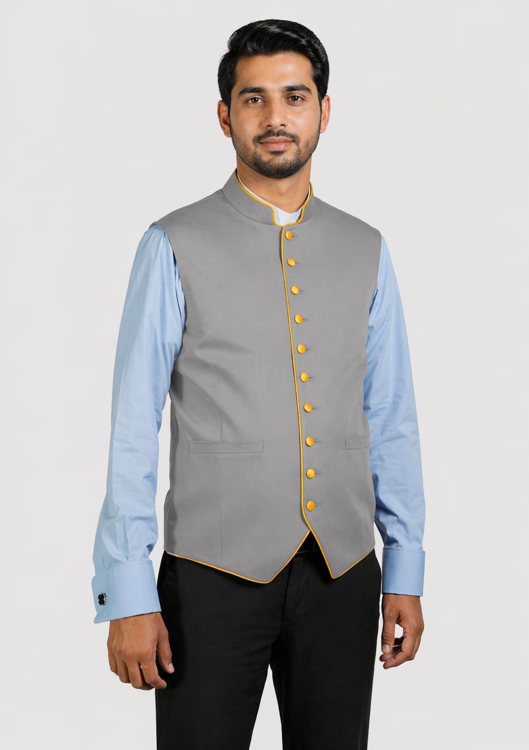 Man wearing a gray vest with yellow buttons over a light blue shirt on a white background