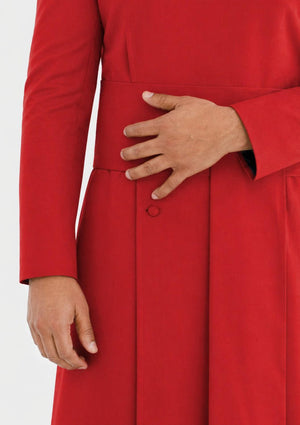 Red coat with a hand on the hip against a white background