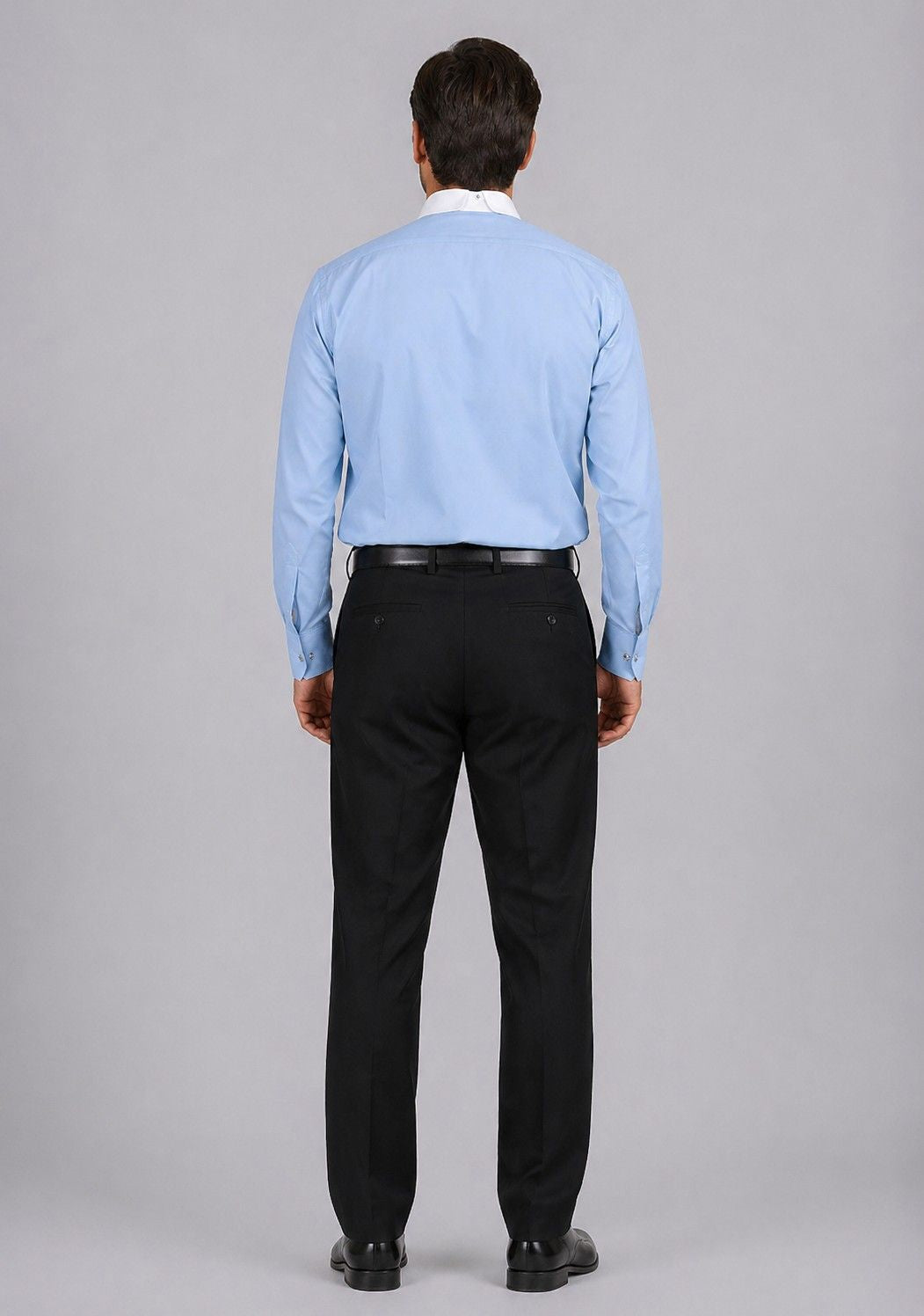 Man wearing a light blue shirt and black pants on a gray background