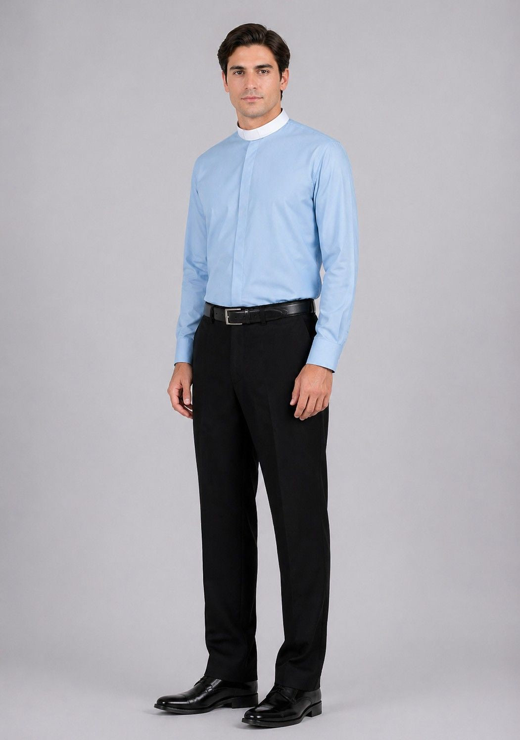 Man wearing a light blue dress shirt and black pants on a gray background