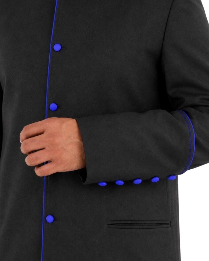 Close-up of a black cassock with bright blue trim and matching blue buttons, worn by a model whose hand is visible at the front.