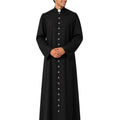 A man modeling a long-sleeved black clerical cassock with a high collar and a white clerical collar tab at the neck, standing against a plain white background.