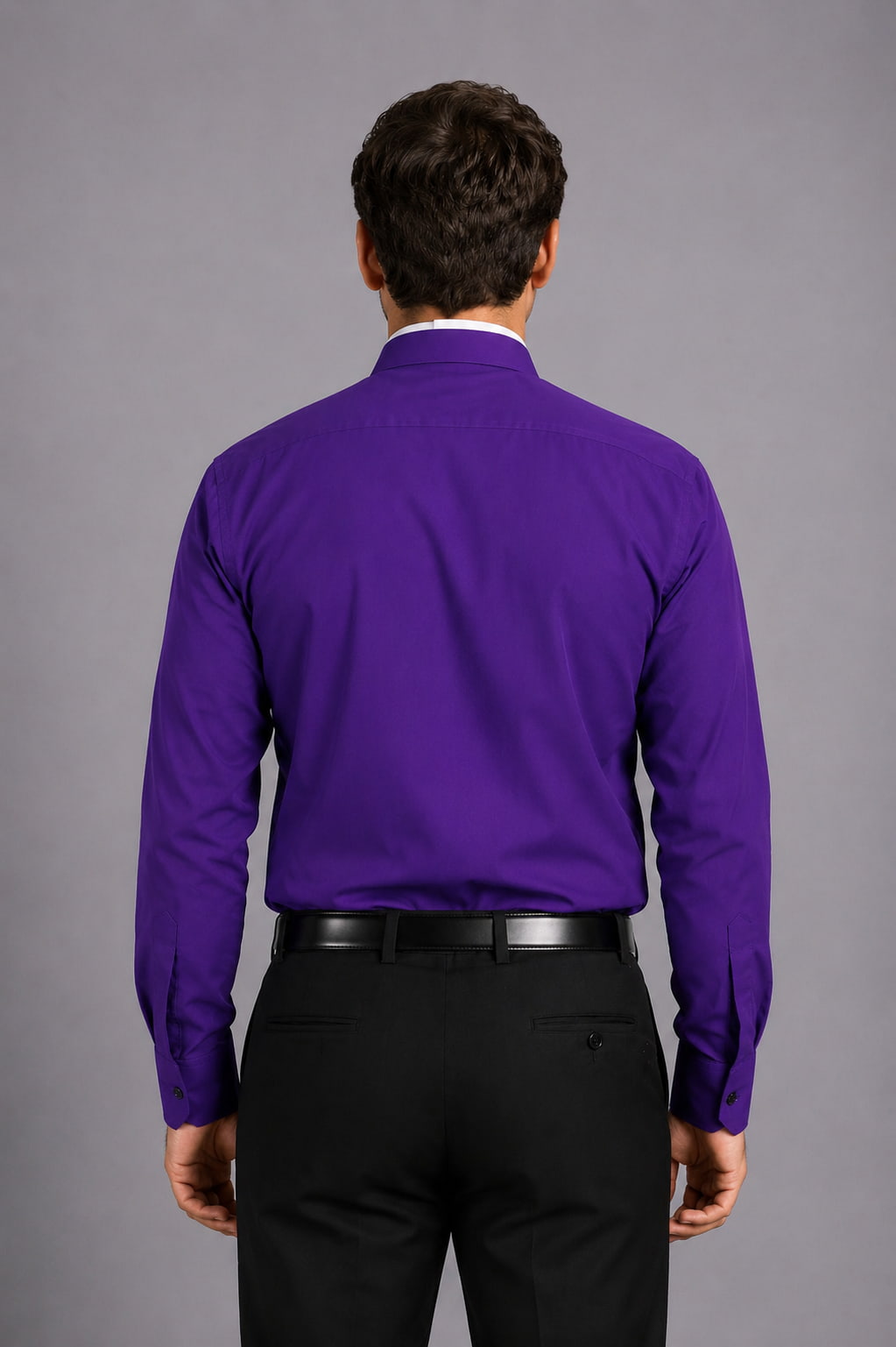 Man wearing a purple shirt with a clerical collar against a gray background