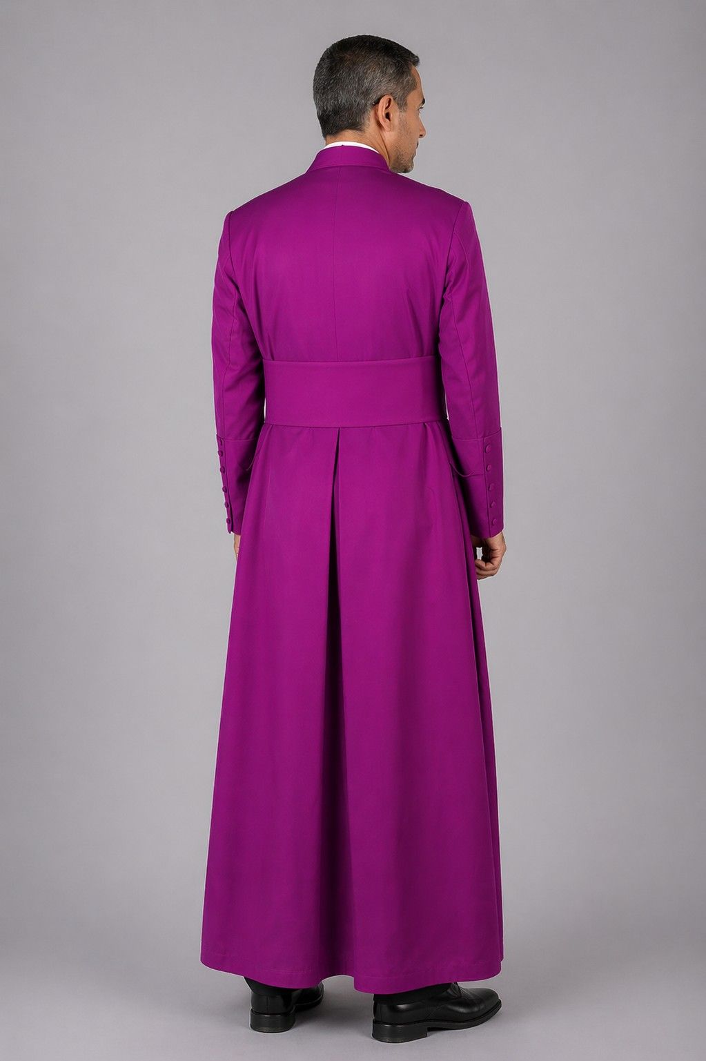 Man wearing a long purple robe against a gray background