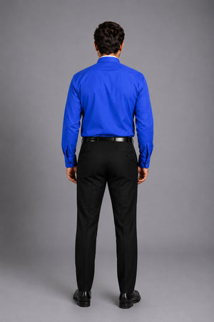 Man wearing a blue shirt and black pants against a gray background