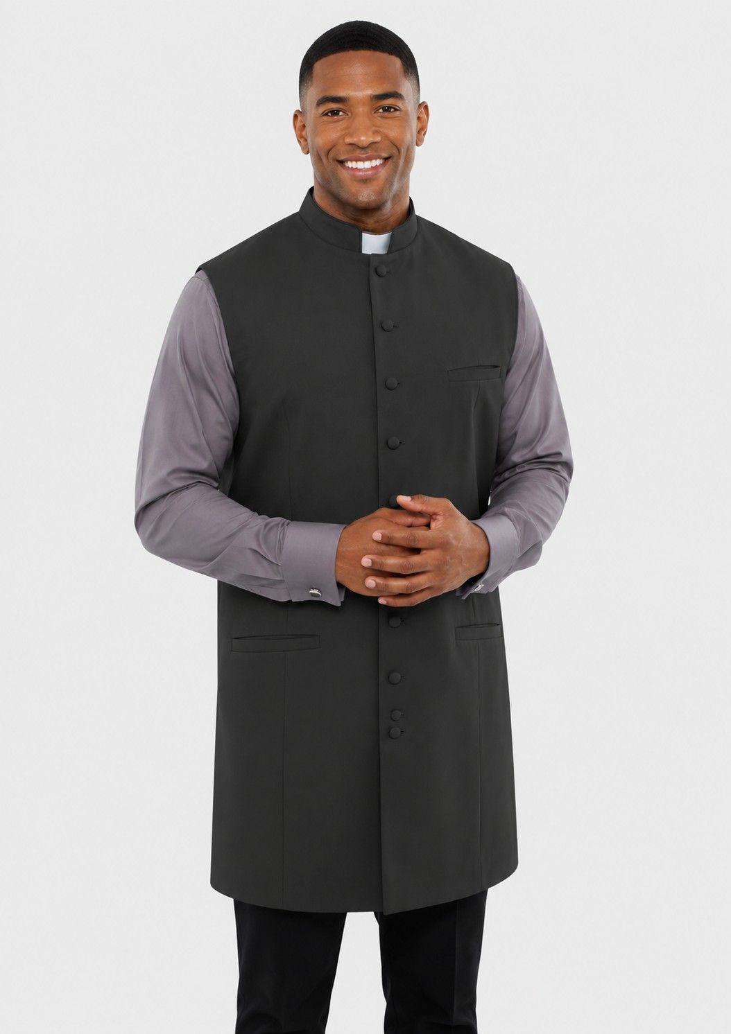 Man wearing a long dark vest over a light shirt on a white background