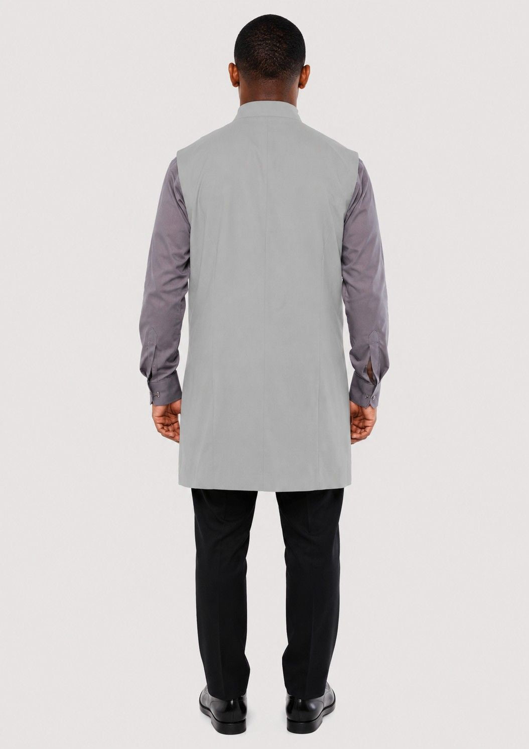 Man wearing a gray long shirt with a vest over a white background