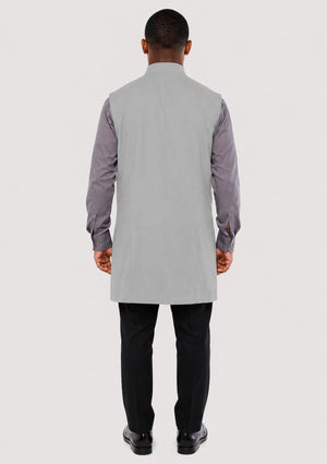 Man wearing a gray long shirt with a vest over a white background
