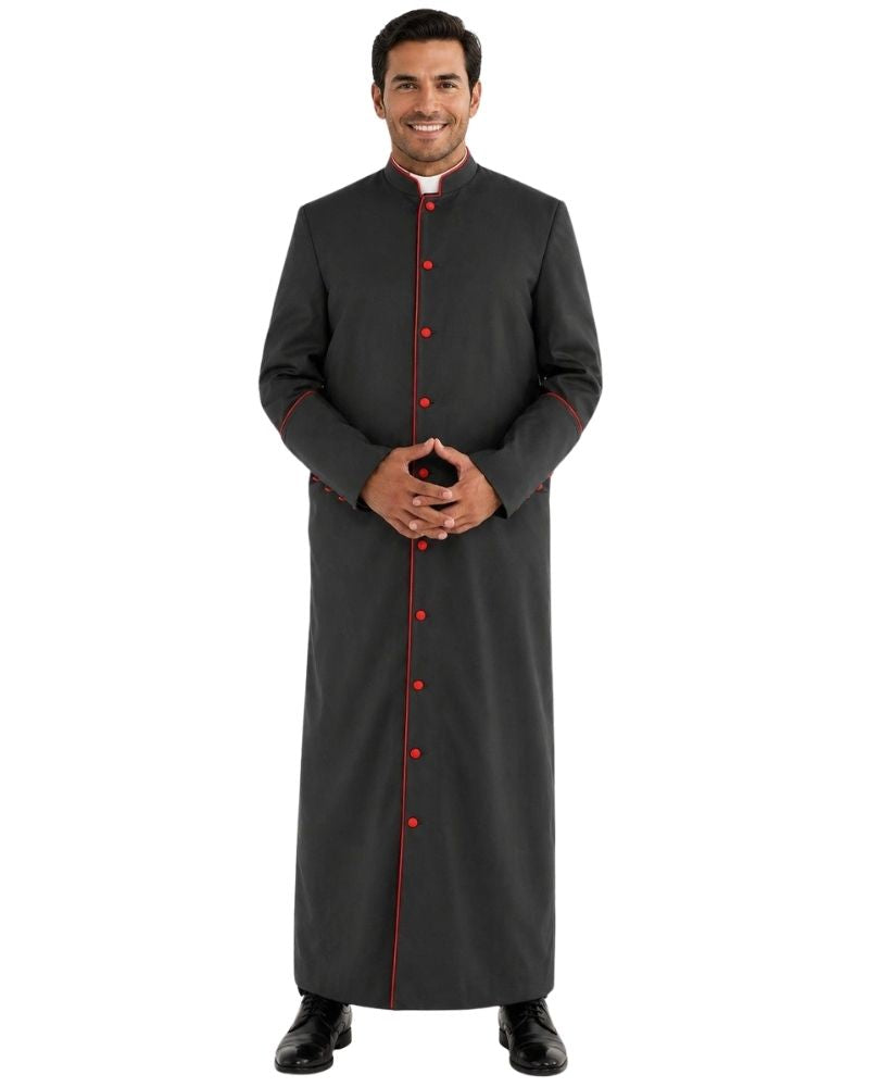 A man modeling a long dark gray clerical cassock with red trim and red buttons, standing against a plain white background.
