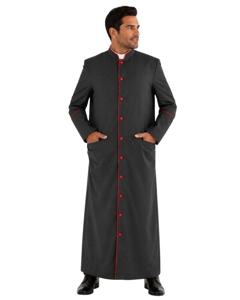 A man modeling a long black clerical cassock with red button accents and red piping details, standing against a plain white background.