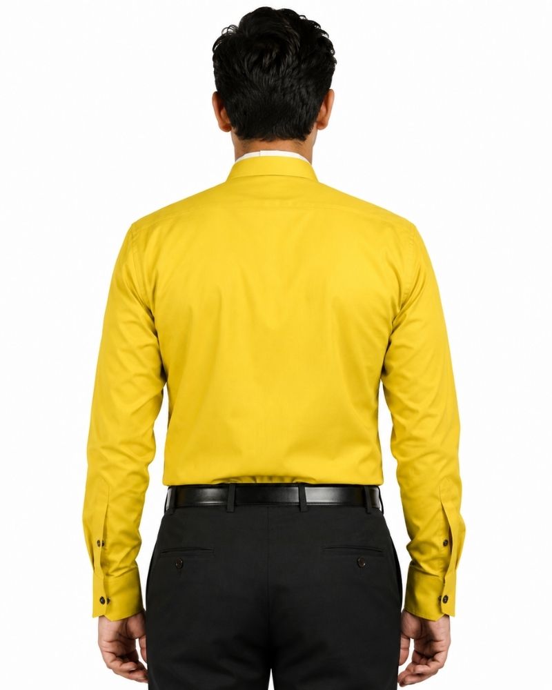 A man viewed from the back wearing a bright yellow long-sleeve clerical shirt tucked into black trousers with a black belt, against a plain white background.