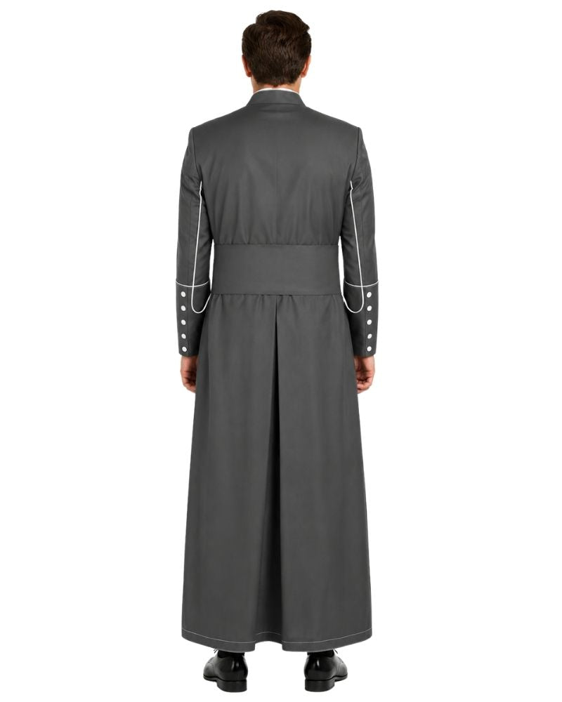 A man viewed from the back wearing a long dark gray cassock with white piping details along the shoulders and sleeves, set against a plain white background.
