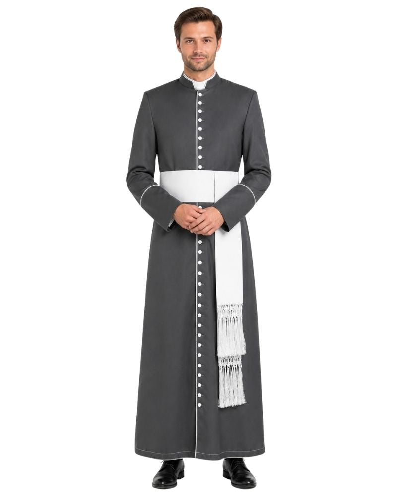 A man modeling a dark gray priestly cassock with a white waist sash, white collar, and white decorative fringes, set against a plain white background.