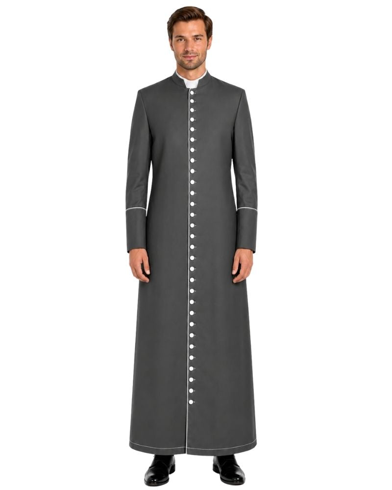 A man modeling a long dark gray clerical cassock with white piping and a white collar, standing against a plain white background.