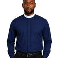 A man wearing a navy blue long-sleeve clerical shirt with a white collar, paired with black trousers and a black belt, photographed against a solid white background.