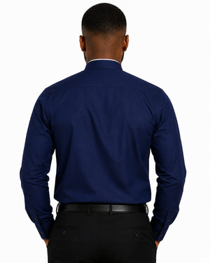 A man viewed from the back wearing a navy blue long-sleeve clerical shirt with a white inner collar, paired with black trousers and a black belt, against a plain white background.