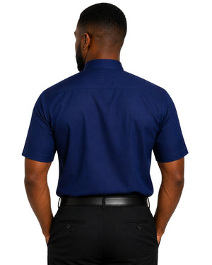 A man viewed from the back wearing a navy blue short-sleeve clerical shirt and black trousers, isolated on a white background.