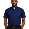 A man wearing a navy blue short-sleeve clerical shirt with a white collar tab, paired with black trousers and a black belt, against a plain white background.