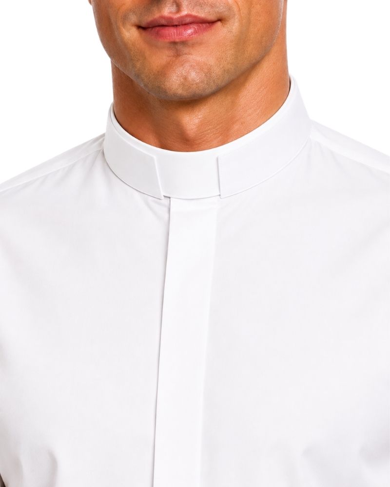 A close-up of a man wearing a white long-sleeve clerical shirt with a high collar and a white clerical collar, set against a plain white background.