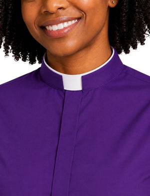 A close-up of a smiling woman wearing a purple clerical shirt with a white collar, set against a plain white background.