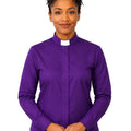 A woman wearing a purple long-sleeve clerical shirt with a white collar, standing against a plain white background.