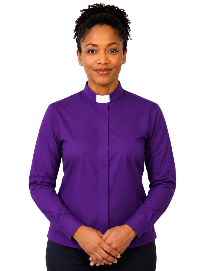 A woman wearing a purple long-sleeve clerical shirt with a white collar, standing against a plain white background.