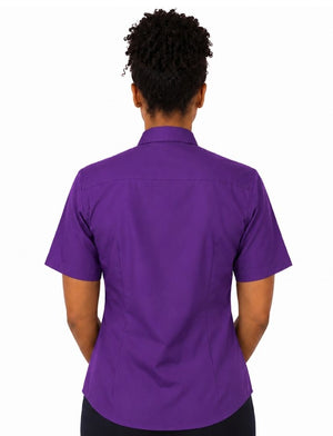 A woman viewed from the back wearing a short-sleeve purple clerical shirt and black bottoms, set against a plain white background.
