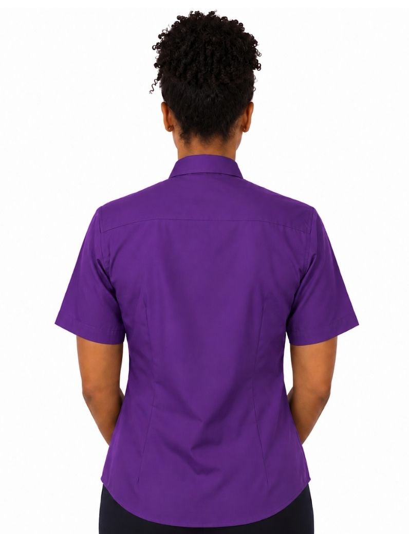 A woman viewed from the back wearing a short-sleeve purple clerical shirt and black bottoms, set against a plain white background.